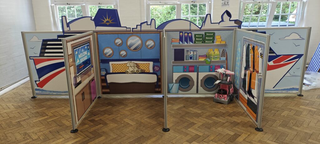 Complete flat-pack role-play village installation featuring freestanding scenic panels and interactive props ready for play onboard P&O Cruises.