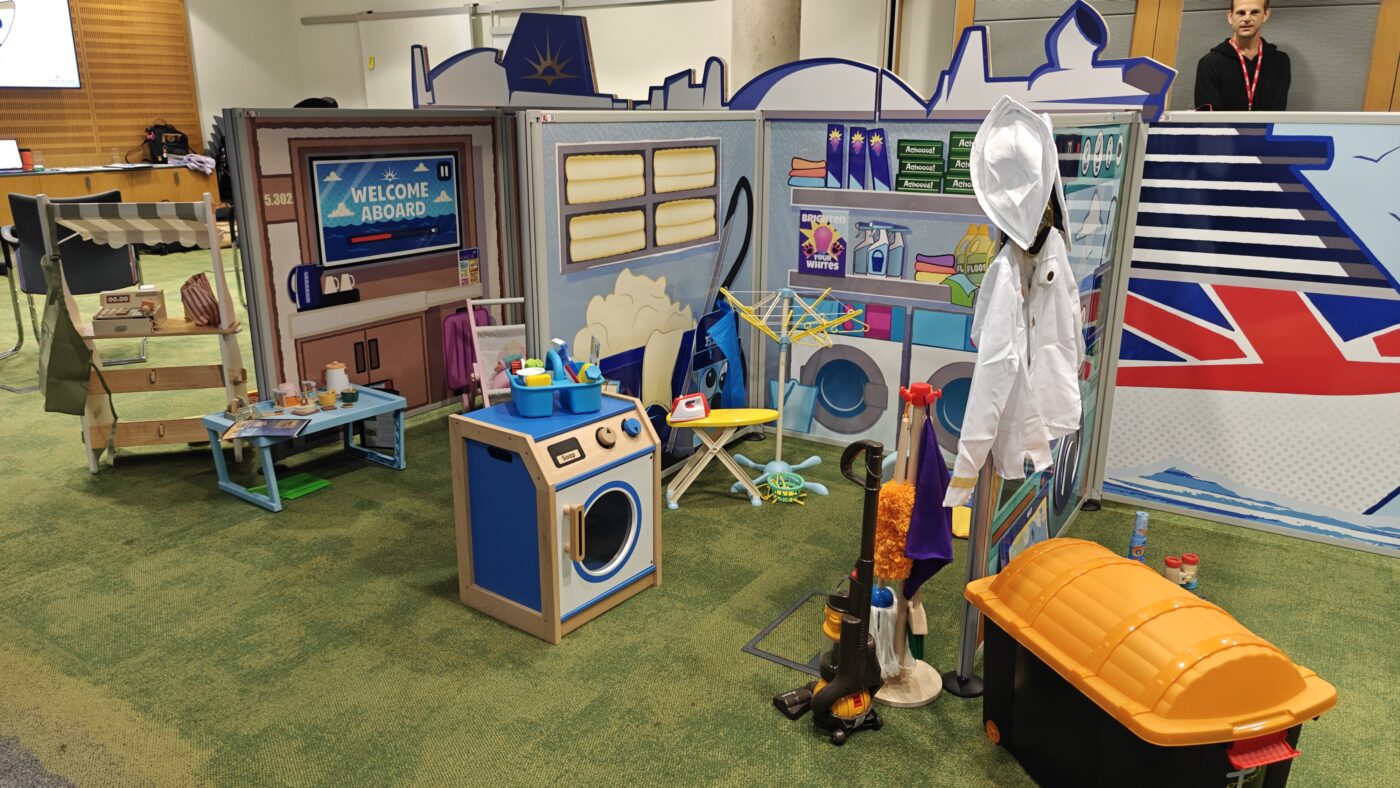 Modular housekeeping play zone panel fully dressed with custom wooden steering wheel, navigation props, and tactile toys.