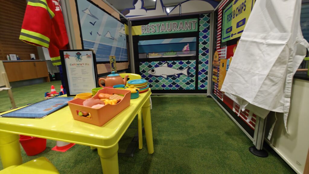 Modular restaurant play zone panel fully dressed with custom wooden steering wheel, navigation props, and tactile toys.