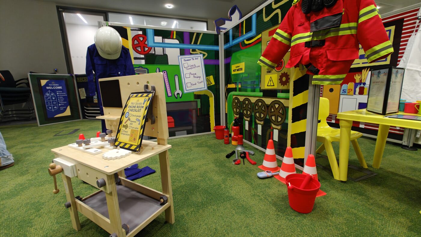 Bespoke shipboard play props, costume accessories, and tactile learning toys displayed against custom scenic panels.